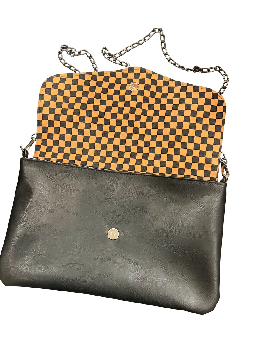 Midnight Check envelope bag open to show orange-and-black checkerboard lining, magnetic snap, and chain strap.